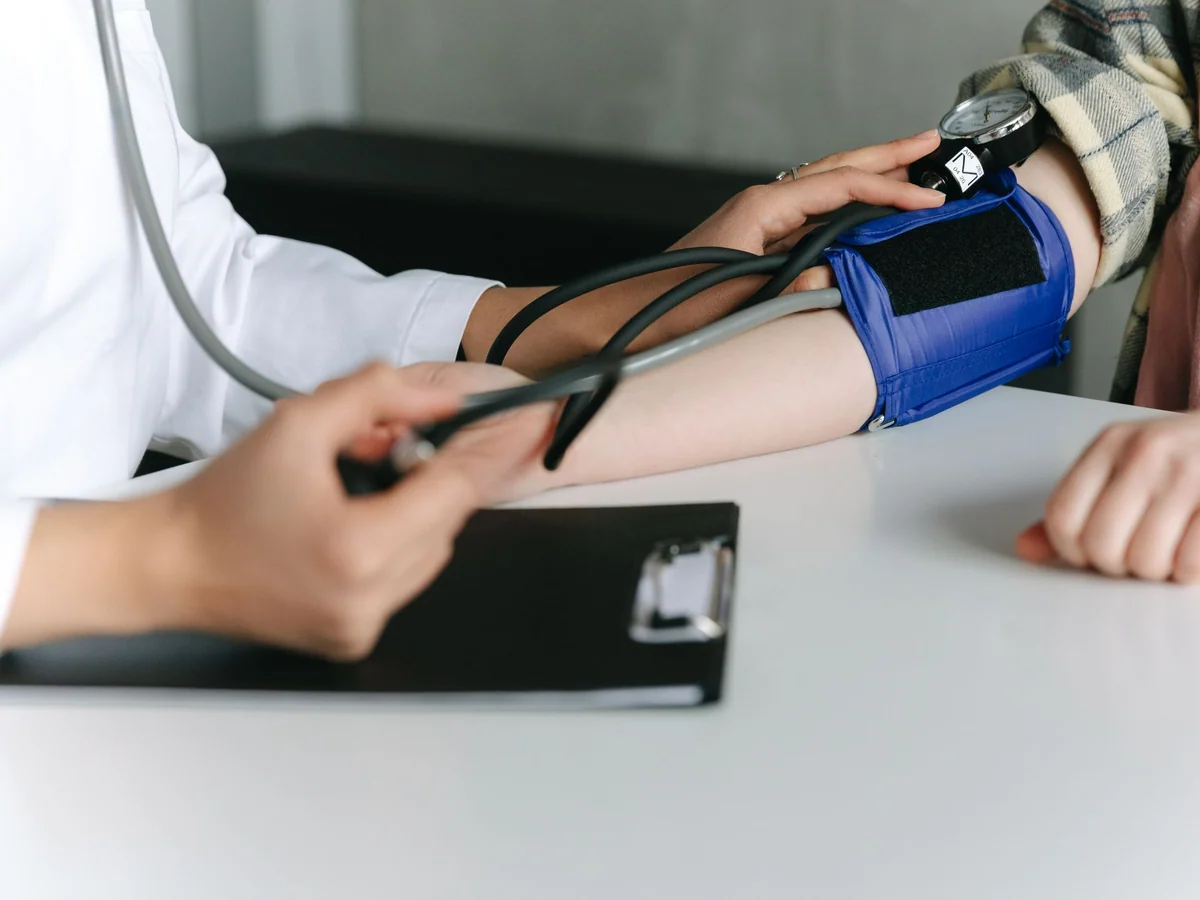 Woman measuring blood pressure at home with an upper-arm monitor