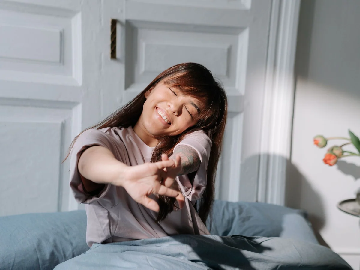 Woman adjusting bedding in a temperature-conscious bedroom