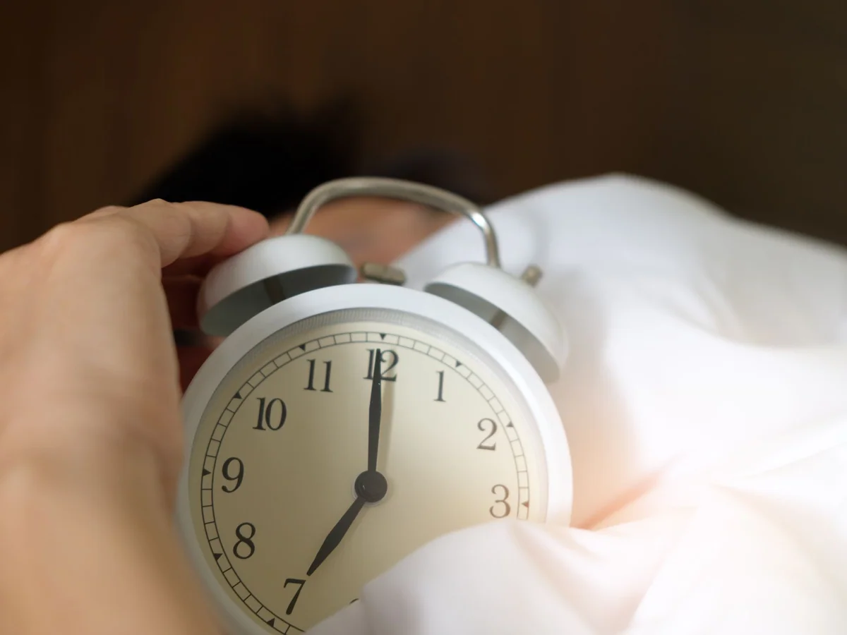 Woman waking beside a gradually brightening sunrise alarm